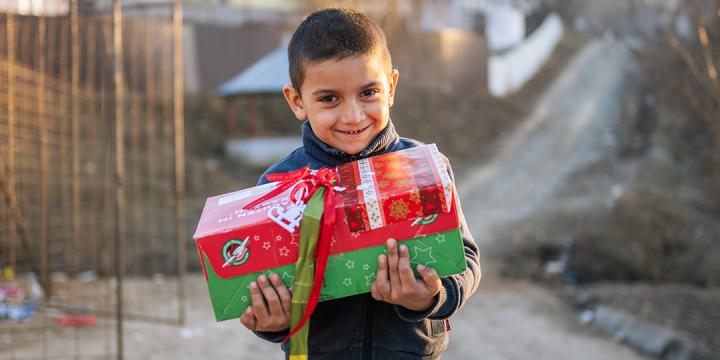 Smiling boy holding his Operation Christmas Child gift shoebox